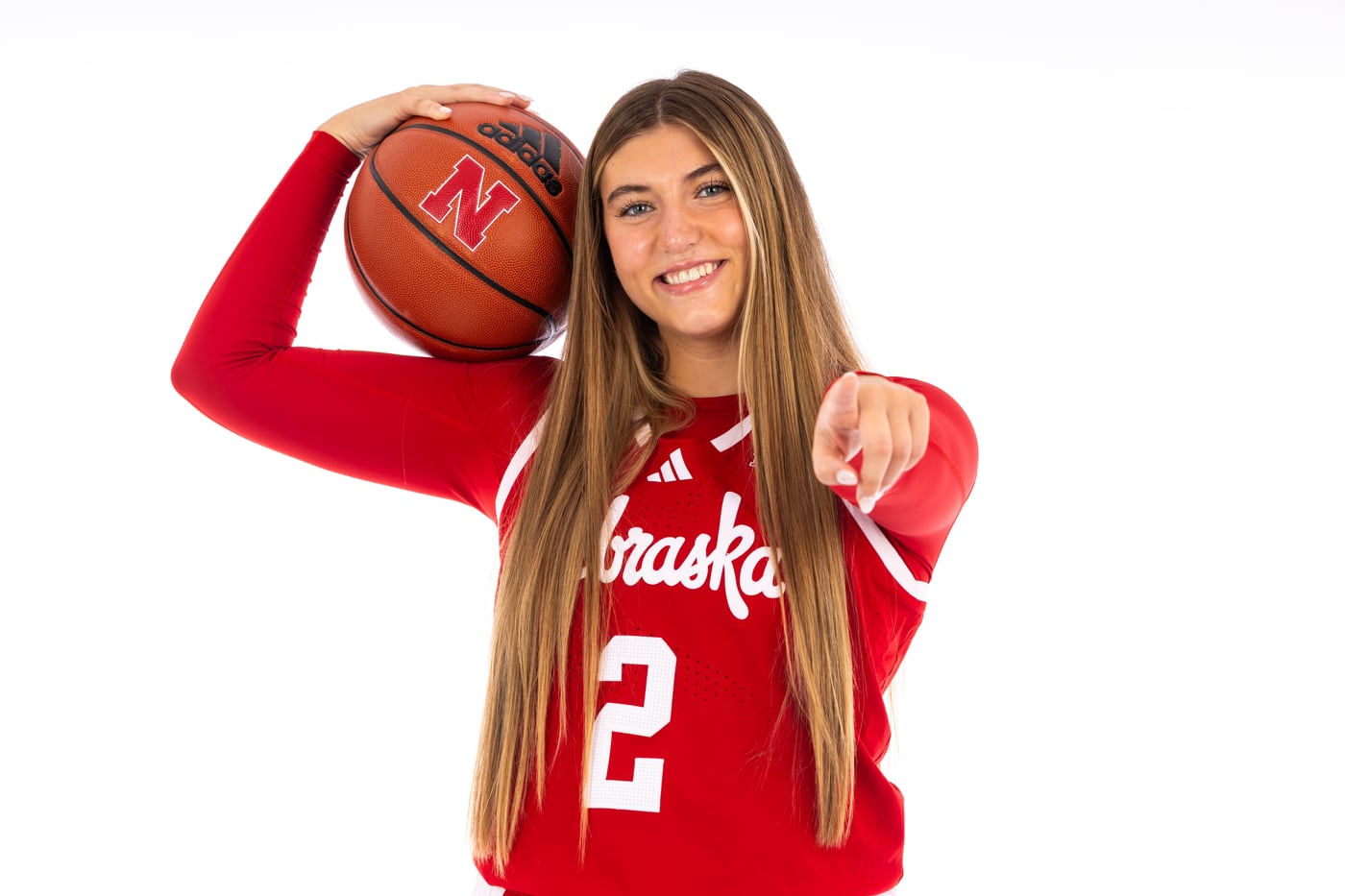 Logan Nissley pointing at the camera while holding a Nebraska basketball
